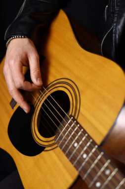 Akustik gitar çalan bir adamın eli. Yakın plan.