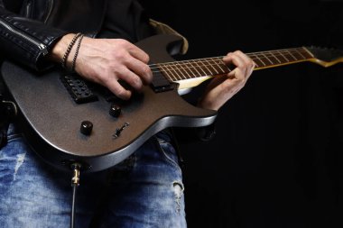 Deri ceketli, elektro gitar çalan müzisyen.