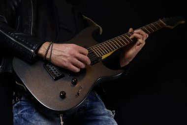 Gitarist siyah arka planda elektro gitar solosu çalıyor.