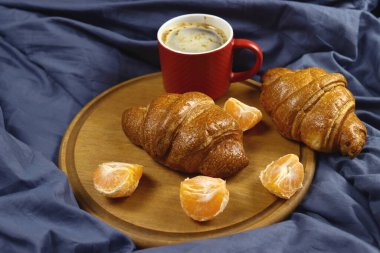 Kahvaltı yatakta kahve, kruvasan ve mandalinayla.