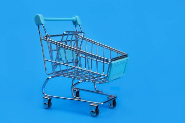Mavi arka planda boş bir alışveriş arabası