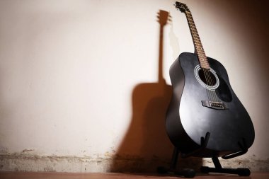 Klasik alçı duvarlı arka planda gölgeli akustik gitar. Metin için boşluk