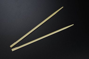 Ahşap yemek çubukları, siyah arka planda suşi çubukları.