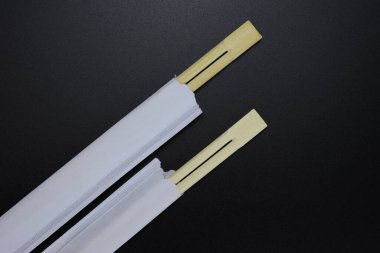 Tahta yemek çubukları, siyah arka planda kağıda sarılı suşi çubukları.