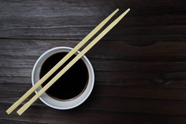 Ahşap yemek çubukları, suşi çubukları ve arka planda soslu tencere.