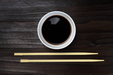 Ahşap yemek çubukları, suşi çubukları ve arka planda soslu tencere.