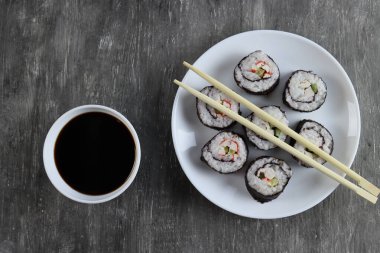 Salatalıklı taze suşi ruloları, yengeç çubukları ve koyu arkaplanda soya sosu.