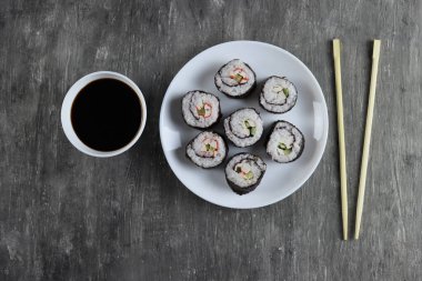 Salatalıklı taze suşi ruloları, yengeç çubukları ve koyu arkaplanda soya sosu.