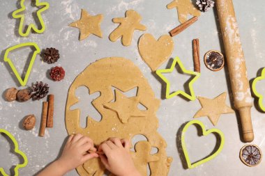 Masanın üzerinde kurabiye şeklinde hamurdan zencefilli kurabiye yapıyorlar.