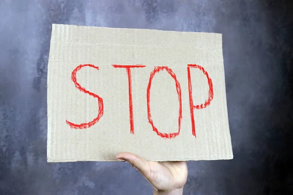 Zettel Mit Dem Wort Stop Der Hand Auf Grauem Hintergrund — Stockfoto