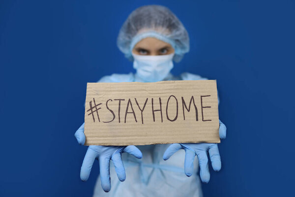 Doctor holding stay at home sign. Urges people to stay indoors, fight coronavirus