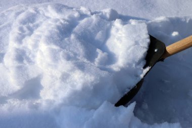 Bir kürekle yolu kardan temizliyorum.
