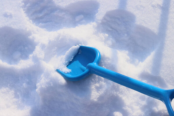 child cleans snow with a toy shovel after a snowfall