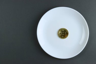 Altın sikke Bitcoin, gri bir sırtüstü beyaz bir tabakta