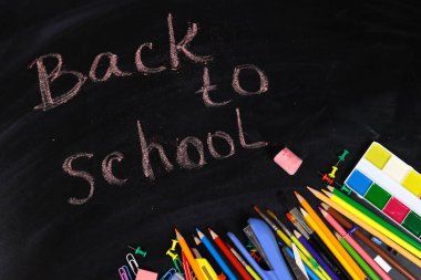 Renkli kalem, boya, fırça ve kırtasiye düz karatahta yatıyordu, okula dönüş konsepti