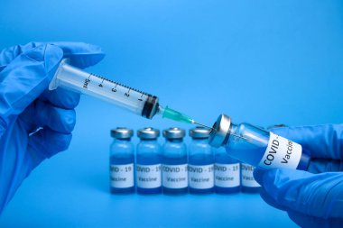 Doktor, hemşire koronavirüs aşısını bir ampulden şırıngaya çeviriyor.