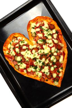 Kalp şeklinde pizza, sevgililer günü için bir tepside.