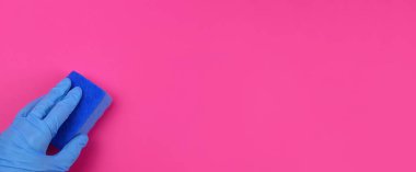 Eldivenin içinde pembe bir arka planda temiz bir sünger bezi var. Yatay Pankart