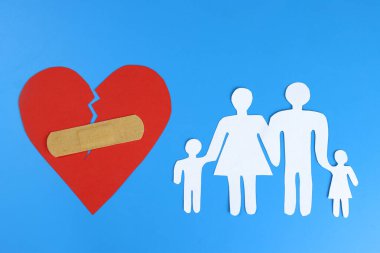 Aile kağıttan yapılmış ve kalp yara bandıyla mühürlenmiş. Boşanma kavramı, aile koruması.