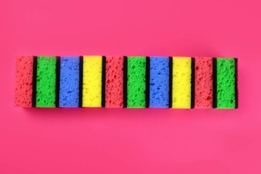 Renkli süngerler, pembe arka planda bulaşık yıkamak ya da temizlemek için çamaşır bezleri.