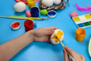 Çocuk mavi arka planda Paskalya için yumurtaları gösteriyor