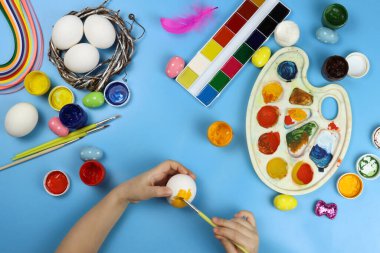 Çocuk mavi arka planda Paskalya için yumurtaları gösteriyor