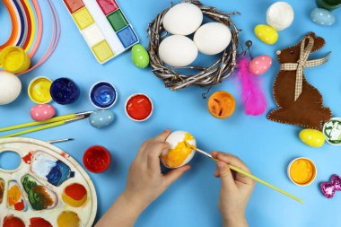 Çocuk mavi arka planda Paskalya için yumurtaları gösteriyor