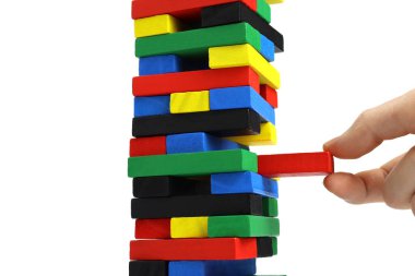 Erkek eli, kuleden beyaz arka planda izole edilmiş ahşap bir tuğla çıkarır.