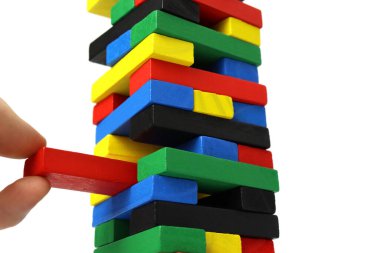 Erkek eli, kuleden beyaz arka planda izole edilmiş ahşap bir tuğla çıkarır.