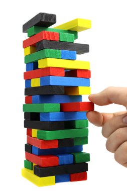 Erkek eli, kuleden beyaz arka planda izole edilmiş tahta bir tuğla çıkarır. Dikey yönelim