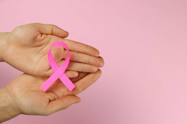 Kadın ellerinde pembe kurdele, göğüs kanseri mücadele sembolü.