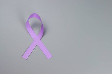 Gri arka planda mor kurdele, aile içi şiddete karşı mücadelenin sembolü.