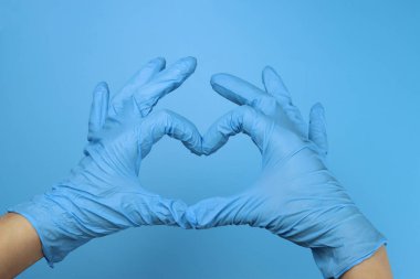 Lateks eldiven giyen bir doktor ya da hemşire kalp hareketi gösterir.