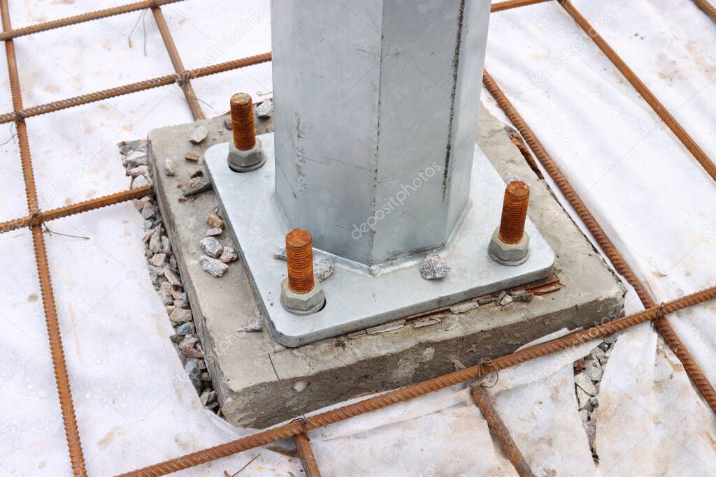 Fixing the iron pillar to the concrete foundation with bolts and nuts close-up