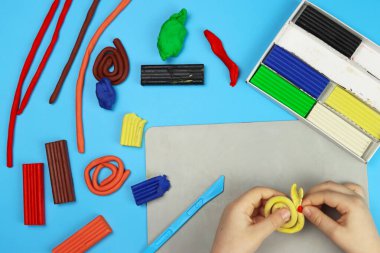 Çocuk renkli plastikten çeşitli figürler yapıyor, elleri yakın plan.