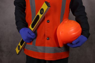 Özel üniformalı mimar koruyucu bir miğfer ve inşaat katı tutuyor, elleri yakın.