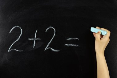 çocuk okul tahtasındaki matematik örneklerini çözer