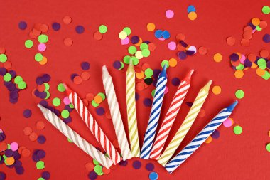 Kırmızı arka planda renkli doğum günü mumları. Kutlama partisi