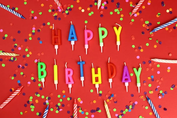 Colorful happy birthday candles on a red background