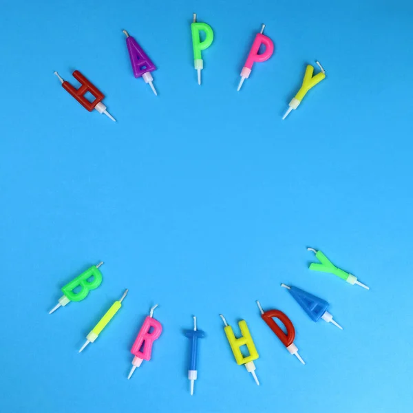 Colorful happy birthday candles on a blue background. Copy space for text