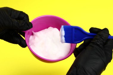 Eldivenli stilist plastik kasede saç boyasını karıştırıyor. Saç boyama konsepti