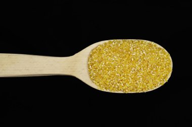 Siyah arka planda tahta kaşıkta ezilmiş mısır.