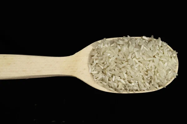 Rohe Reiskörner Einem Holzlöffel Auf Schwarzem Hintergrund — Stockfoto