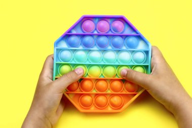 Çocuk elleri rengarenk gökkuşağıyla oynuyor Sarı arka planda patlatın