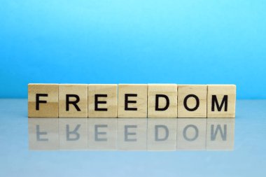 Mavi arka planda tahta bloklardan yapılmış özgürlük kelimesi