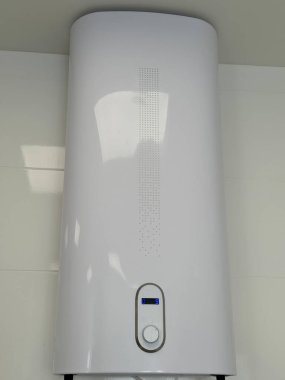 Banyonun duvarına dijital ekran monte edilmiş beyaz su ısıtıcısı.