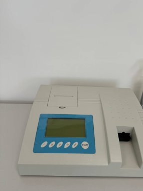 Spektrofotometre beyaz bir laboratuvar çalışma tezgahında kontrol düğmeleri ile boş bir ekran görüntülüyor