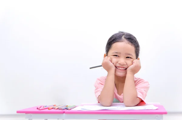 Leende asiatisk liten flicka sitter händer att haka med färg penna — Stockfoto
