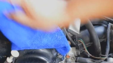 Araba motoru temizlemek için mavi mikro fiber kumaş kullanmak adamın elini