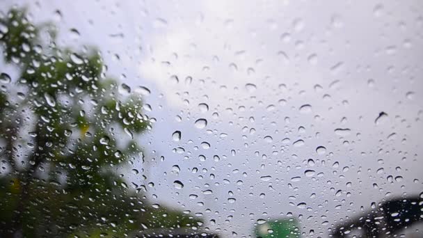 Close up colpo goccia di pioggia sul vetro del finestrino dell'auto e il traffico sfocato su ambiente pioggia nuvoloso sfondo fioco — Video Stock